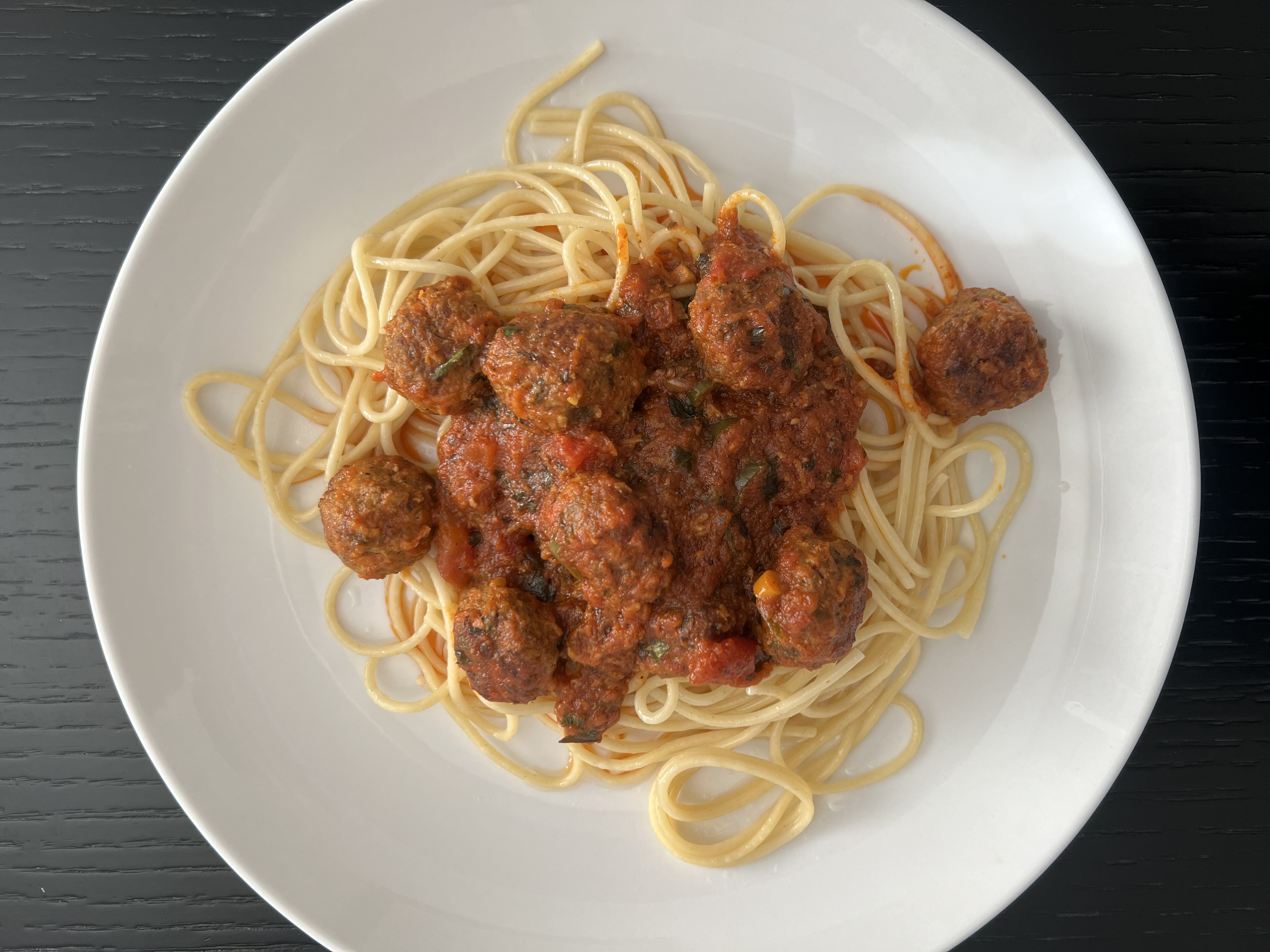 A bowl of cooked spaghetti with sauce and meatballs