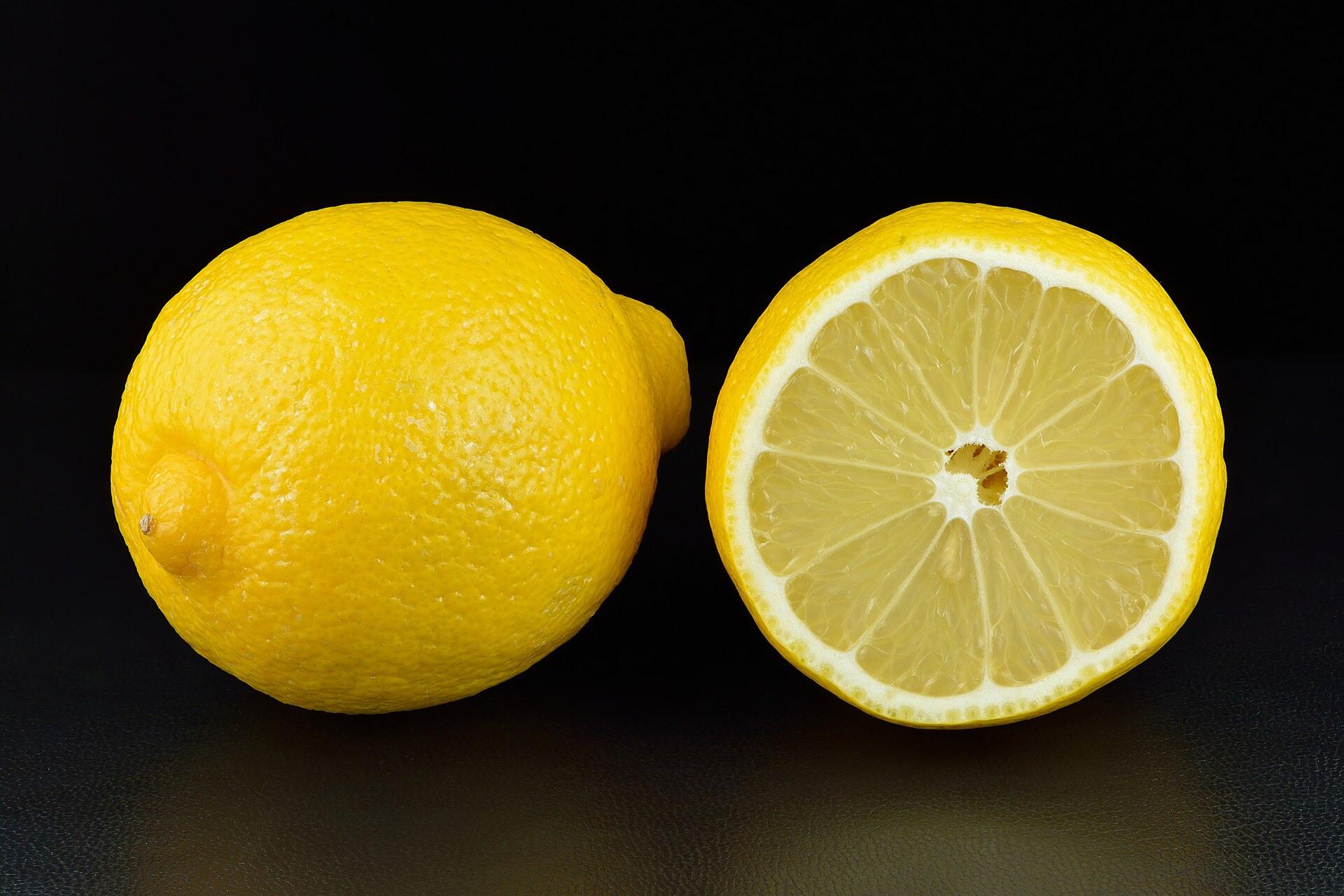A whole lemon beside a halved lemon