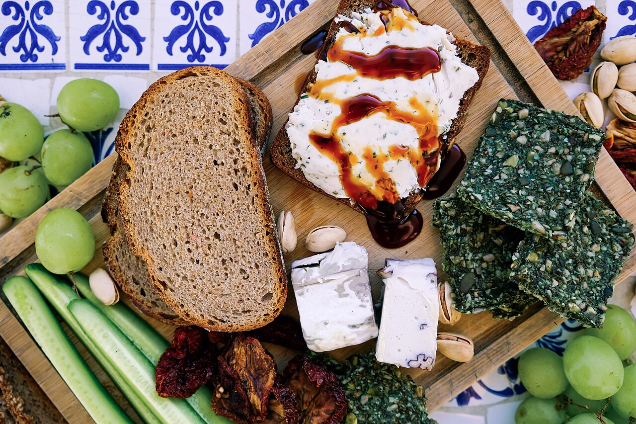 A wooden board with an assortment of hard and soft cheeses