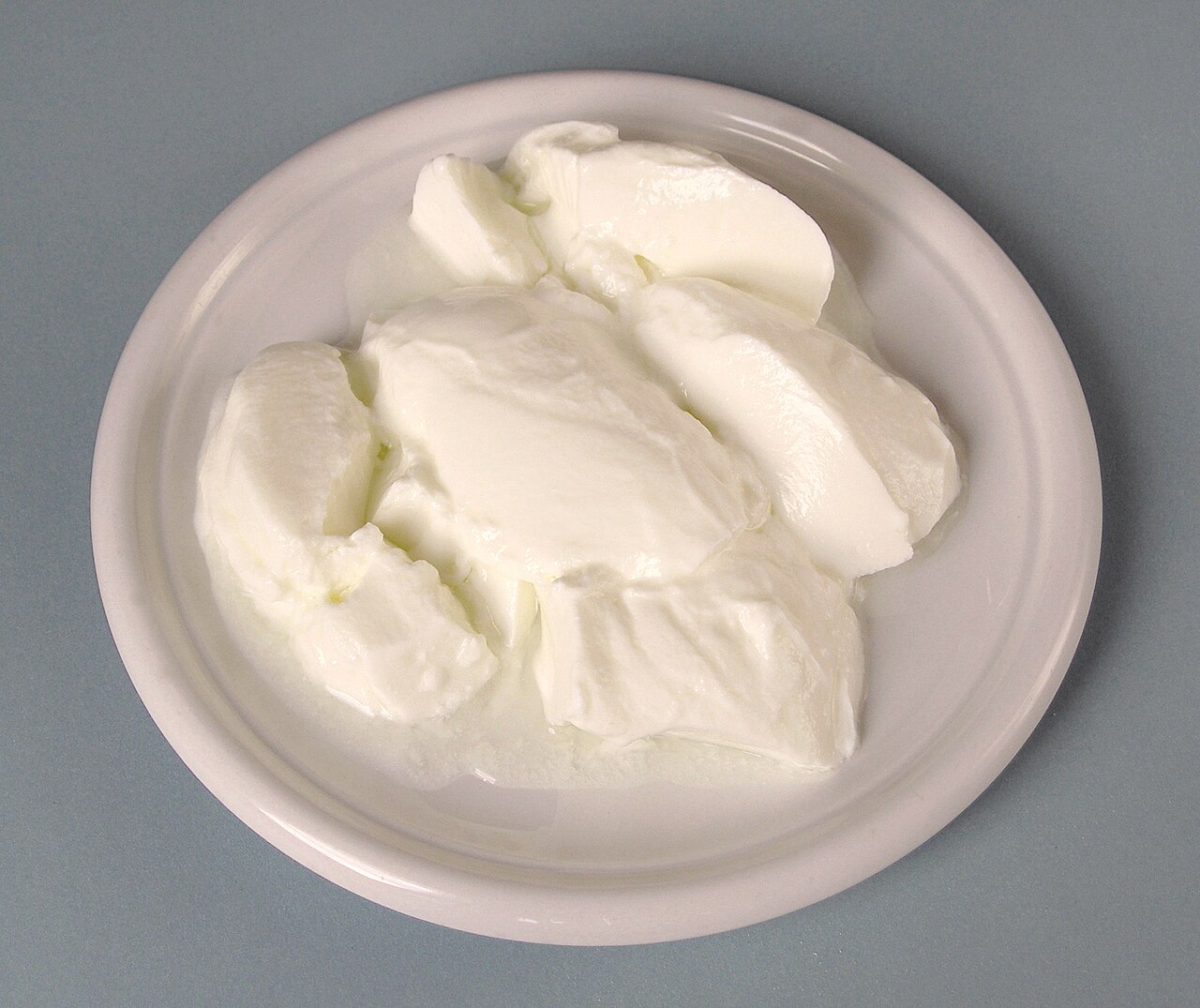 A white bowl of plain natural yoghurt with a spoon