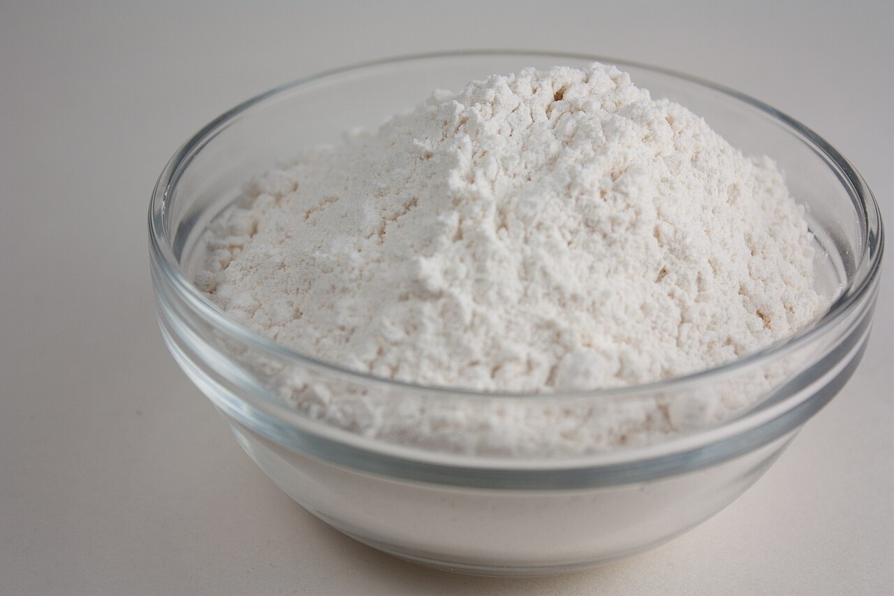 A bowl of plain flour on a wooden surface