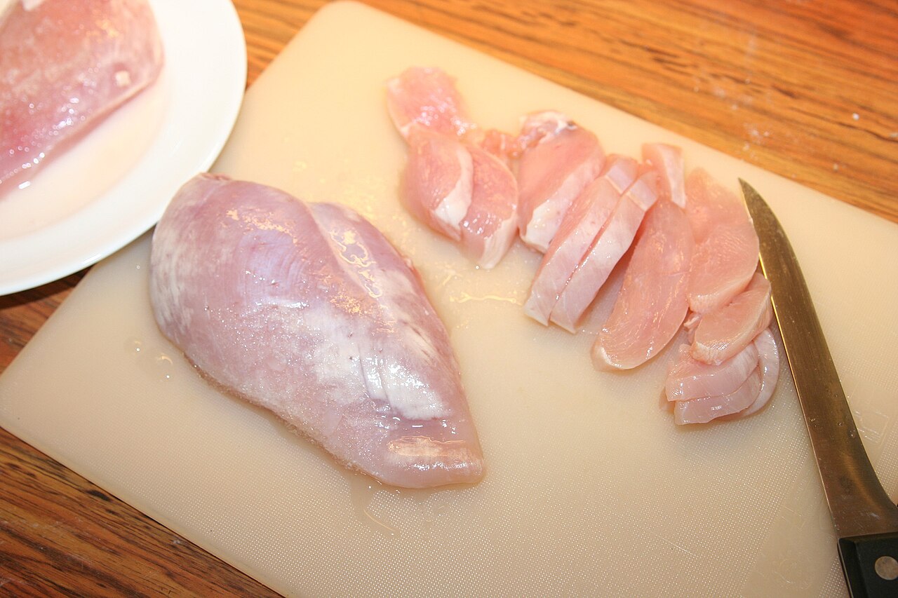 Raw chicken breast fillets on a board
